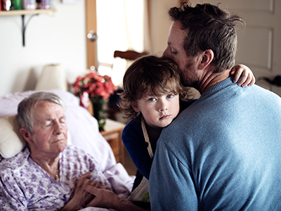 Isabel lies on her bed alongside her son-in-law, Wayne, and 4-year-old grandson, Xavier, in the multi-generational home they share.